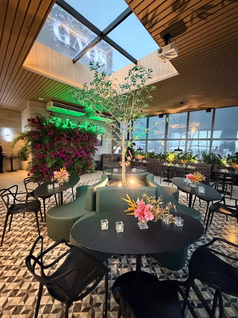 Salão preparado para evento social, com flores e claraboia