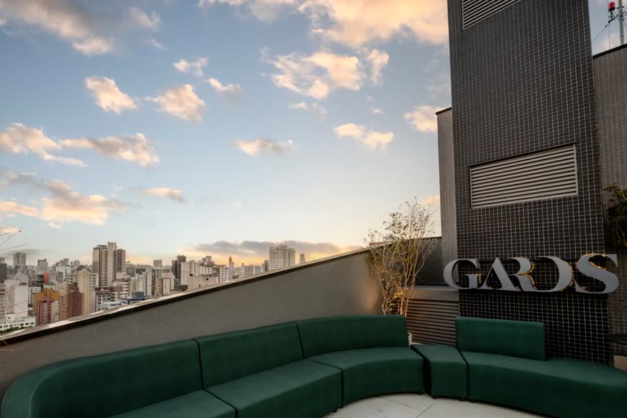 Terraço com sofá verde curvo e o letreiro GARDS na parede
